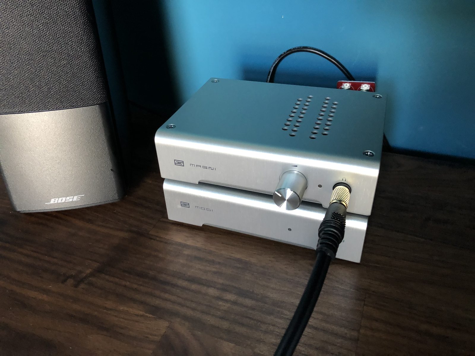 The Schiit stack: a silver Magni headphone amplifier sitting on top of a Modi DAC, with a headphone cable plugged into the front.