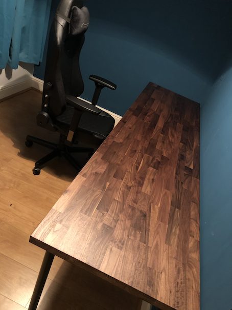 The bare walnut desk before anything was set up on it, with the chair beside it.